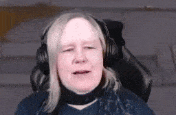 a woman is wearing headphones and a scarf while sitting in a chair .