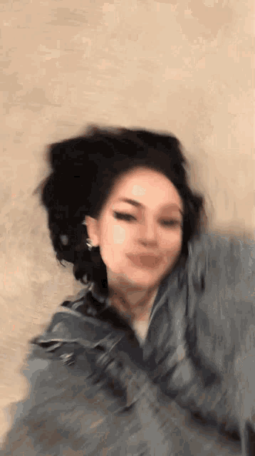 a blurry picture of a girl wearing a denim jacket and earrings .