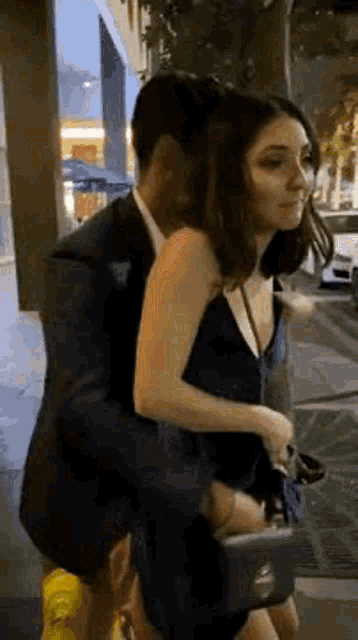 a man in a suit is carrying a woman in a blue dress down a street .