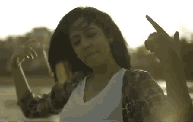 a woman is dancing with her hands in the air and making a peace sign .