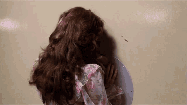 a woman in a floral dress is covering her face with her hand