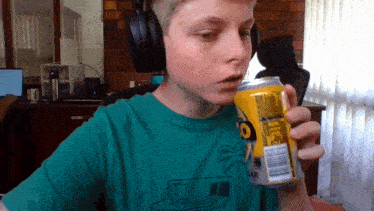 a young boy wearing headphones is drinking a can of coke zero