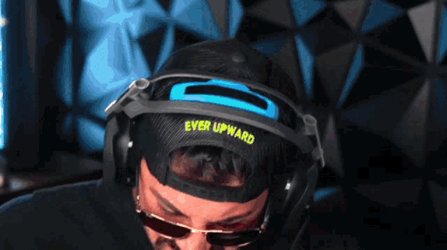 a man wears headphones and a hat that says ever upward
