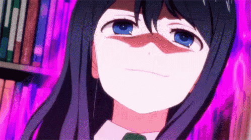 a girl with long black hair and blue eyes is making a face in front of a bookshelf .