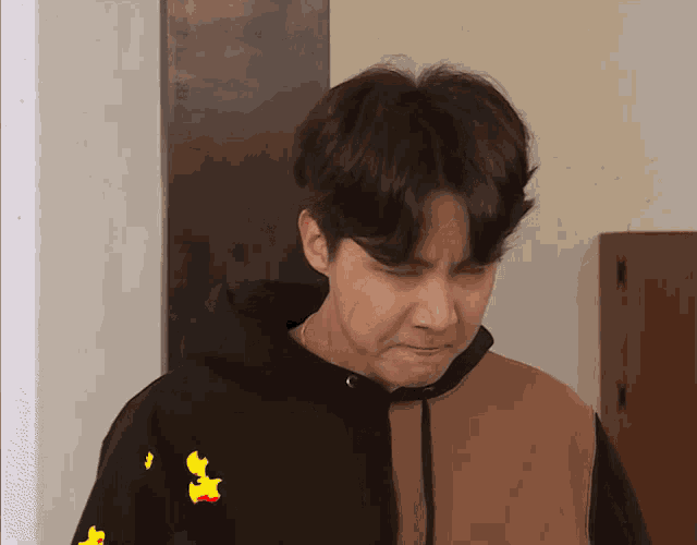 a man wearing a black and brown hoodie has a yellow duck on his back