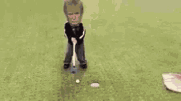 a person is laying on the ground on a golf course next to a golf club and a golf ball .