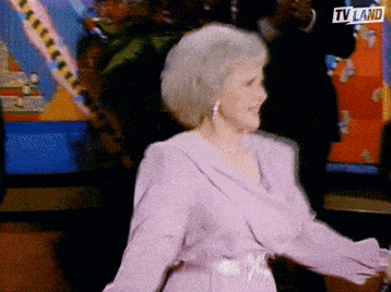 an older woman in a purple dress is dancing in front of a tv screen that says tv land