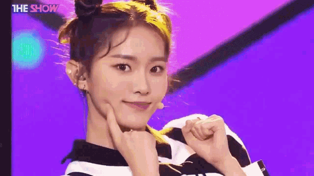 a girl with two buns in her hair is making a funny face on a purple background .