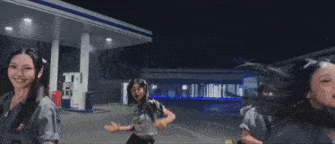 a group of women are dancing in front of a gas station and they are asking " what 's your eta "