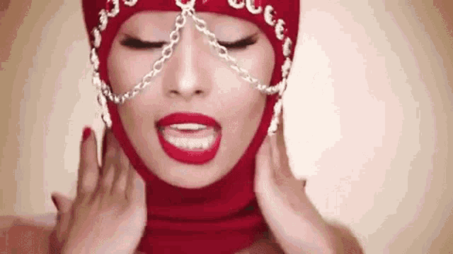a woman wearing a red ski mask with chains around her neck and face .