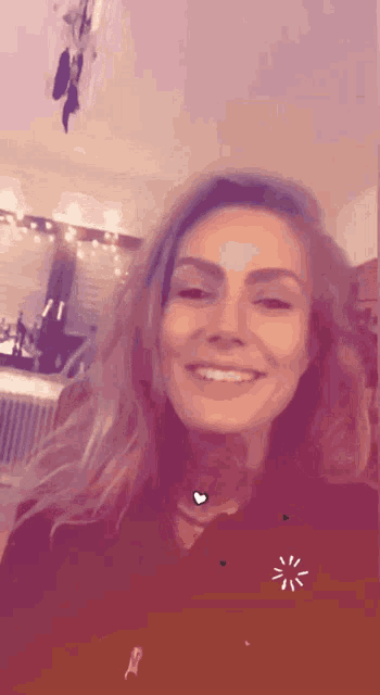 a woman is smiling and wearing a black shirt with a heart on it