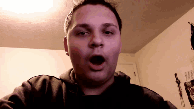 a man with his mouth open is standing in front of a wall with a picture of a man on it