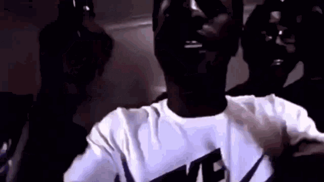 a man wearing a white nike shirt is taking a selfie with a camera .