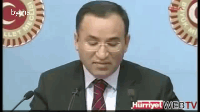 a man in a suit and tie is giving a speech in front of a screen that says bycha on it