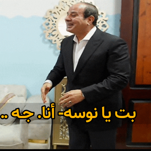 a man in a suit is standing in front of a mirror with arabic writing on the bottom