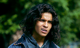 a young man with long curly hair is making a funny face