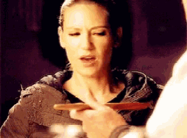 a woman is holding a piece of wood in her hand while looking at another person .