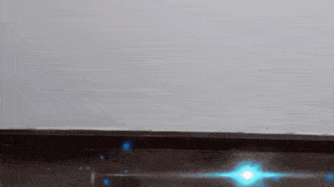 a person 's feet are standing on a wooden floor with a blue light coming out of them