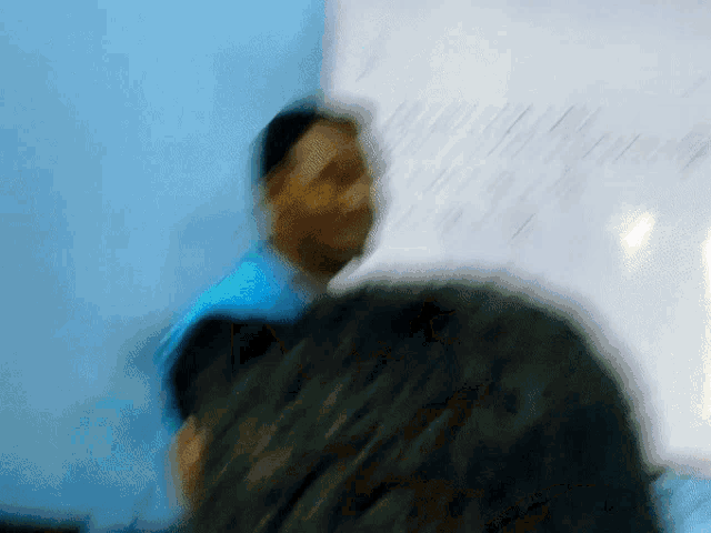 a blurry picture of a man in front of a whiteboard