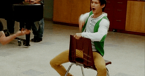 a man in a green vest is sitting in a chair