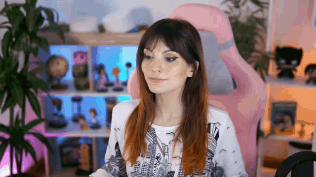 a woman is sitting in a pink gaming chair in front of a computer screen .