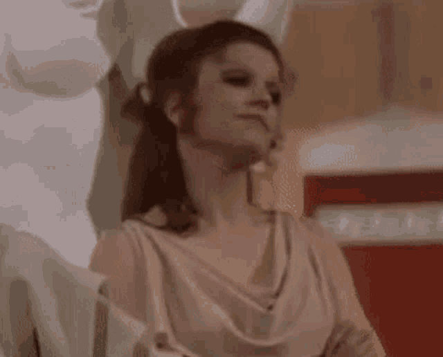 a woman in a white dress is sitting in front of a statue of a man .