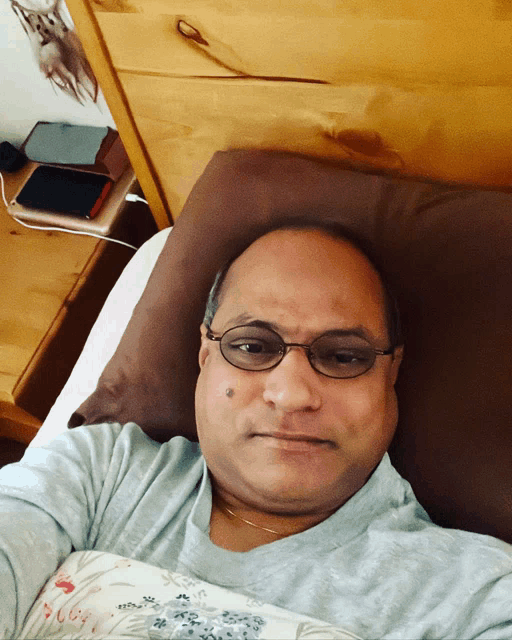 a man wearing glasses is laying in bed with a pillow