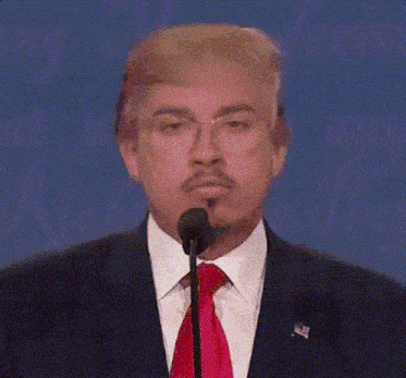 a man in a suit and tie is talking into a microphone with a fake donald trump wig on his head .