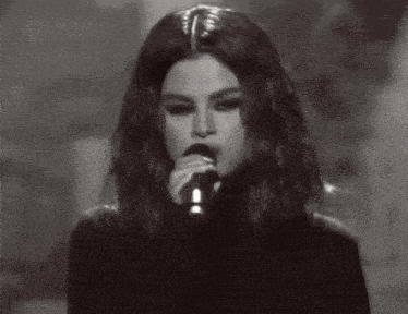 a black and white photo of a woman holding a microphone .
