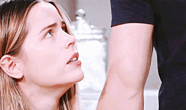 a woman looks up at a man 's arm while he holds her arm