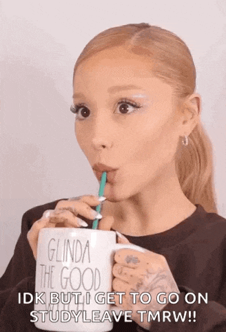 ariana grande is drinking from a coffee mug with a straw .