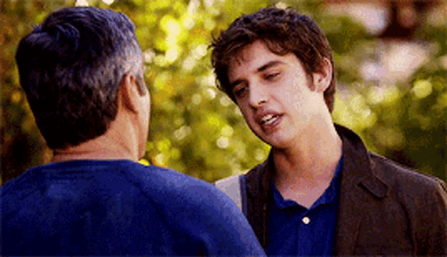 two men are standing next to each other talking to each other