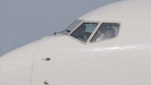a pilot sits in the cockpit of an airplane with a clear window