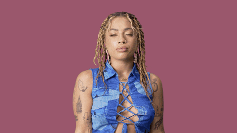 a woman with dreadlocks and tattoos is wearing a blue lace up top .