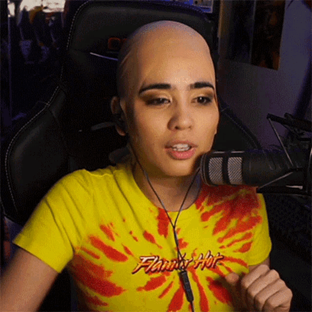 a woman with a bald head is wearing a yellow shirt that says flamin hot