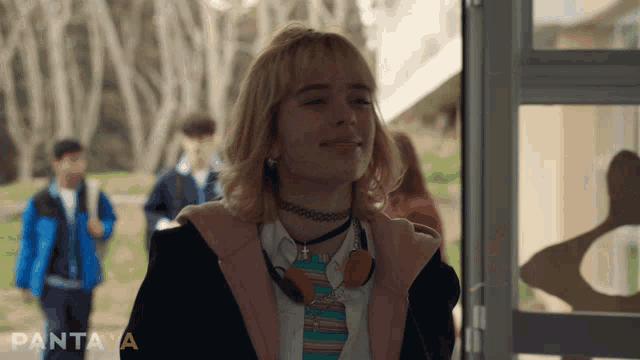 a girl with a choker and headphones is smiling in front of a sign that says pantaya