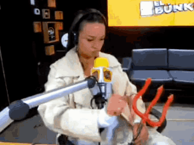 a woman is sitting in front of a microphone and holding a devil 's trident ..