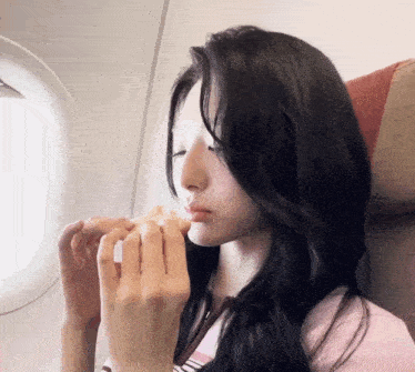 a woman sitting on an airplane eating a snack