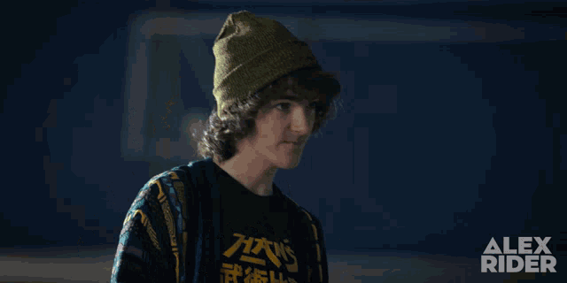 a poster for alex rider shows a young man wearing a green hat