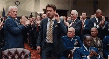 a man in a suit and tie stands in front of a crowd of people