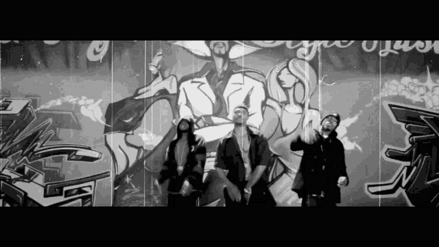 a group of people are standing in front of a wall with graffiti