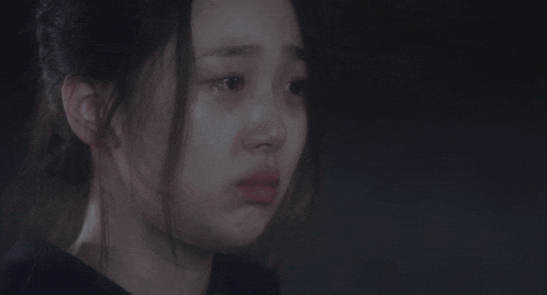 a close up of a woman 's face with her eyes closed and a sad look on her face .