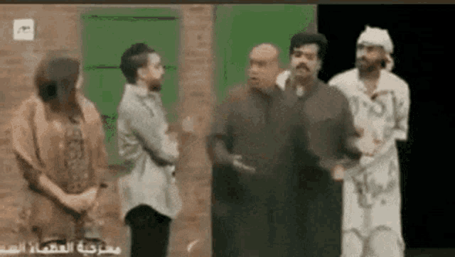 a group of men are standing next to each other in front of a brick wall .