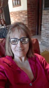 a woman wearing glasses and a pink shirt smiles