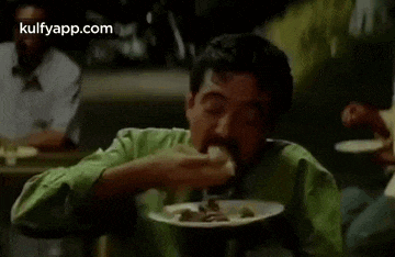 a man with a beard is eating food from a plate in a restaurant .