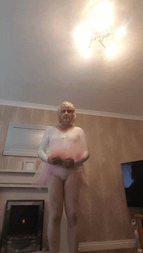a woman in a white leotard and a pink tutu is standing in a living room