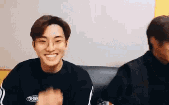 two young men are sitting next to each other on a couch and laughing .