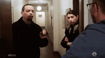 a man is holding a badge and talking to a woman while another man looks on .