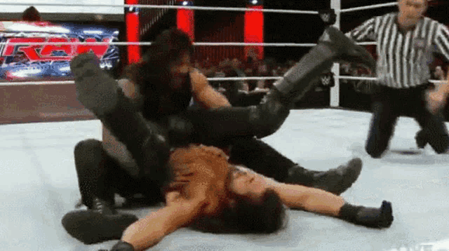 two wrestlers are wrestling in a ring with a referee and a sign that says rm on it