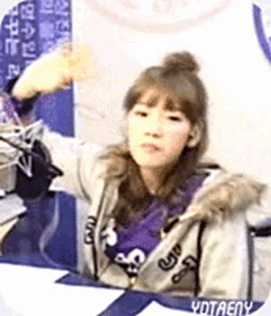a girl in a purple shirt is sitting at a table with a microphone in front of her ..